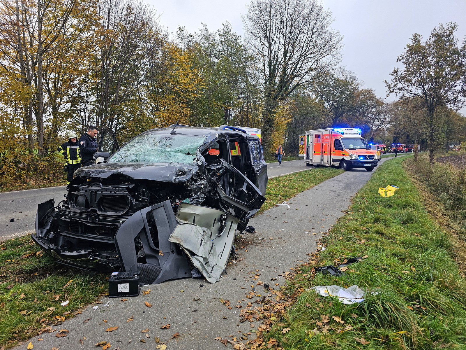 Zerstörtes Auto mit Rettungswagen im Hintergrund