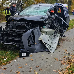 Zerstörtes Auto mit Rettungswagen im Hintergrund