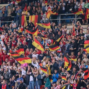 Fans der deutschen Frauen-Fußballnationalmannschaft schwenken Nationalfahnen