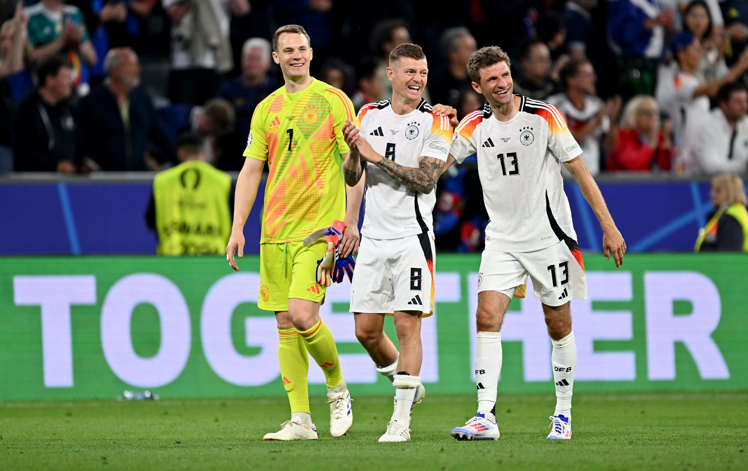 Manuel Neuer, Toni Kroos und Thomas Müller gehen lachend über den Platz bei der EM 2024