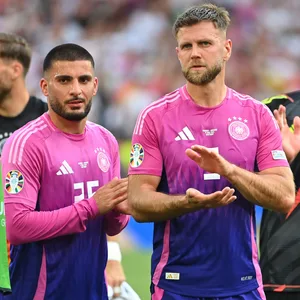 Deniz Undav und Niclas Füllkrug klatschen im DFB-Trikot vor der Fankurve in die ihre Hände