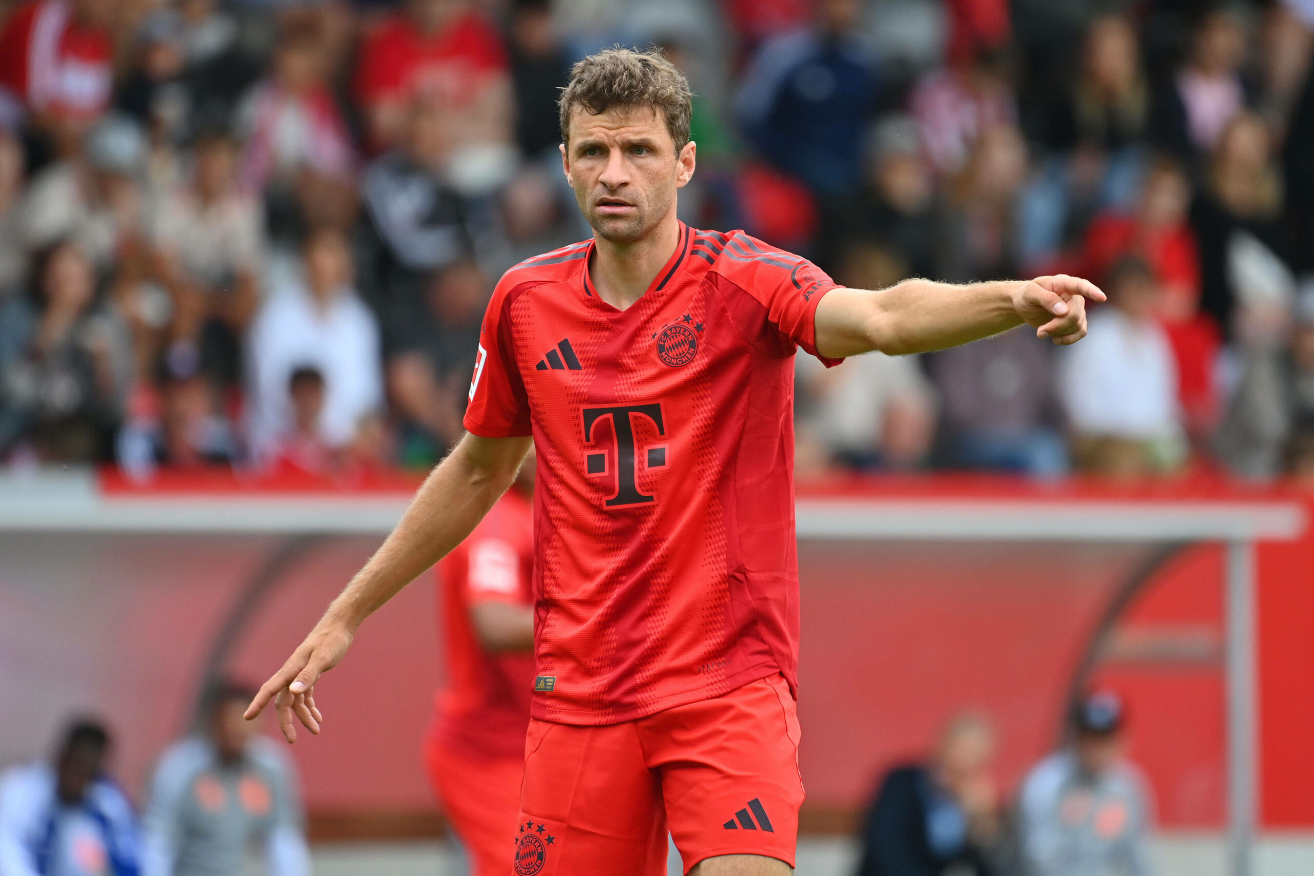 Thomas Müller streckt den Arm auf dem Spielfeld raus