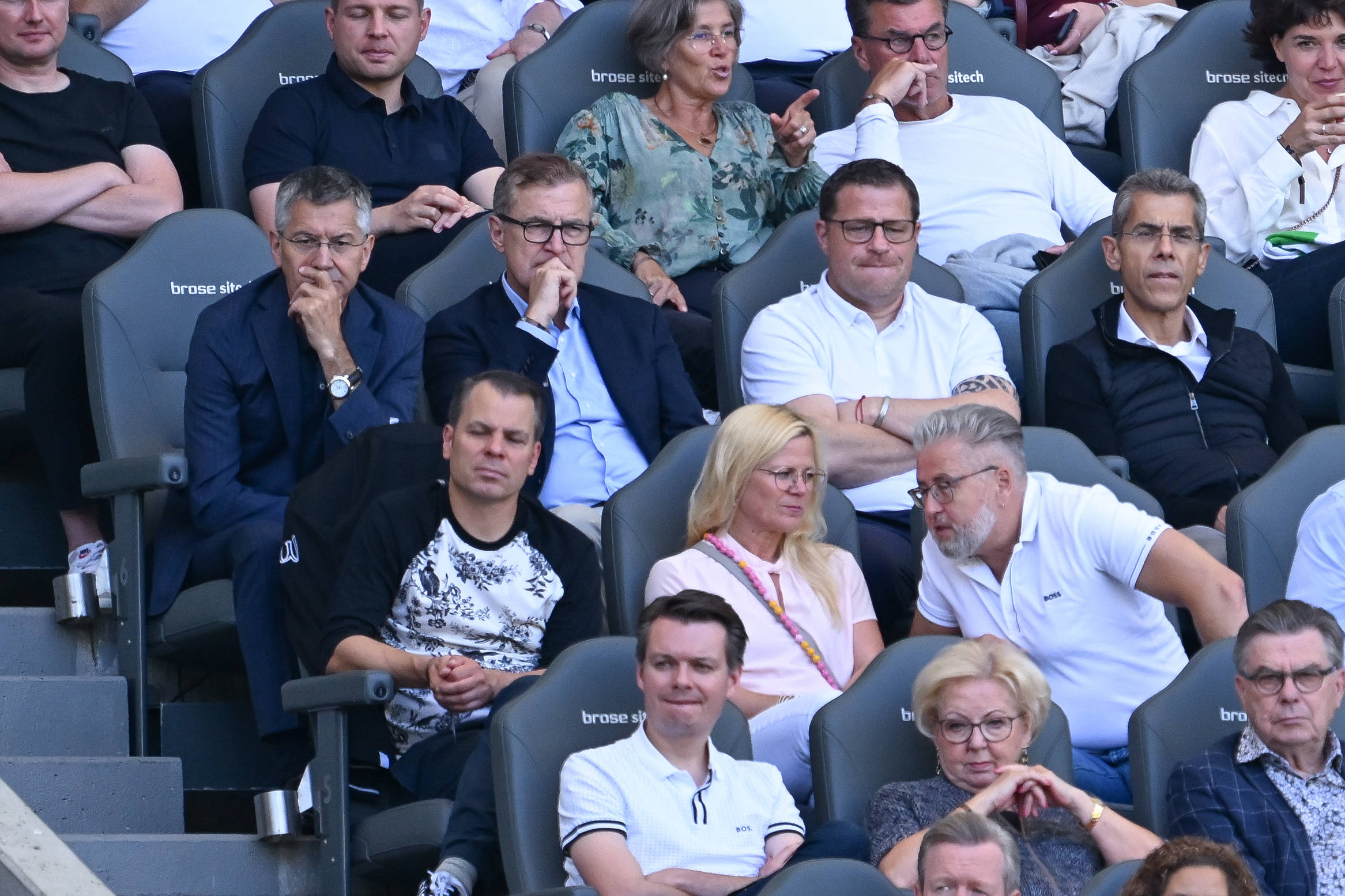 Jan-Christian Dreesen sitzt auf der Tribüne zwischen Herbert Hainer und Max Eberl