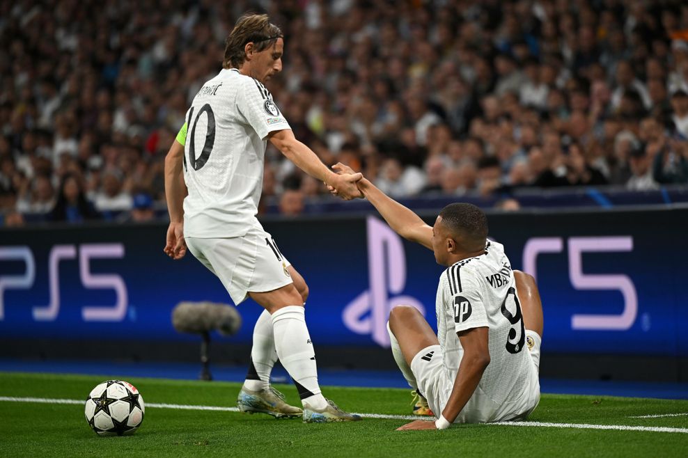 Luka Modric hilft Kylian Mbappe auf.