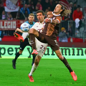 Jackson Irvine schirmt den Ball gegen Thomas Müller ab