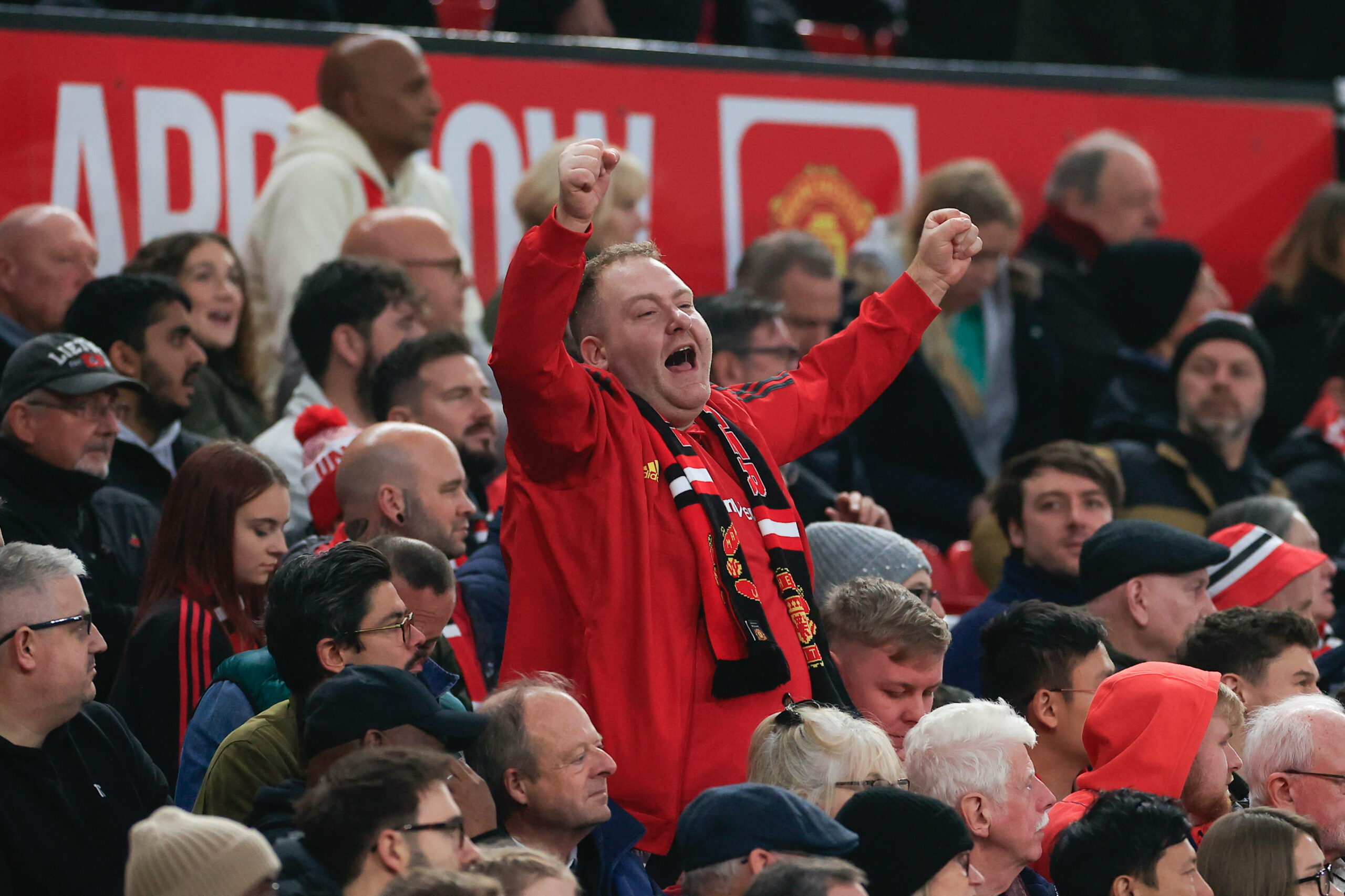 Ein Fan von Manchester United steht auf der Tribüne im Old Trafford und ballt beide Fäuste. Dabei grölt er.