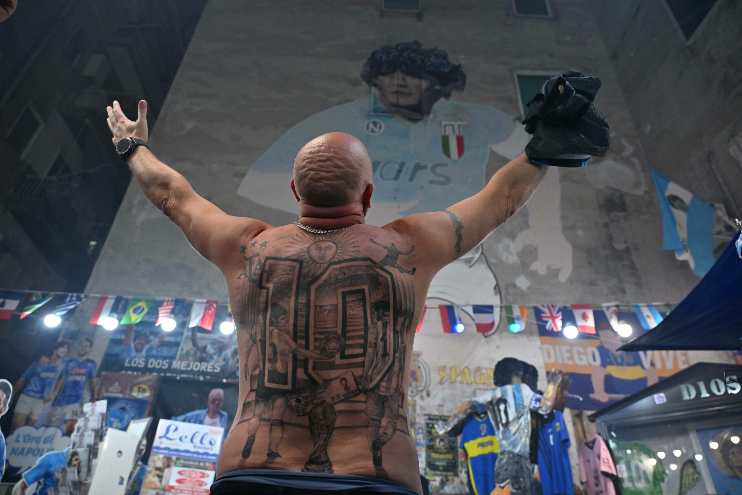 Fans mit tätowiertem Rücken verneigt sich vor einem Maradona-Gemälde in Neapel.