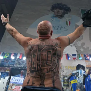 Fans mit tätowiertem Rücken verneigt sich vor einem Maradona-Gemälde in Neapel.