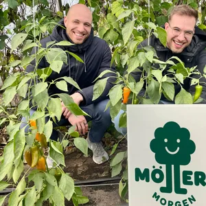 Zwei junge Männer inmitten von Bäumen und mit einem Schild: „Möllers Morgen“