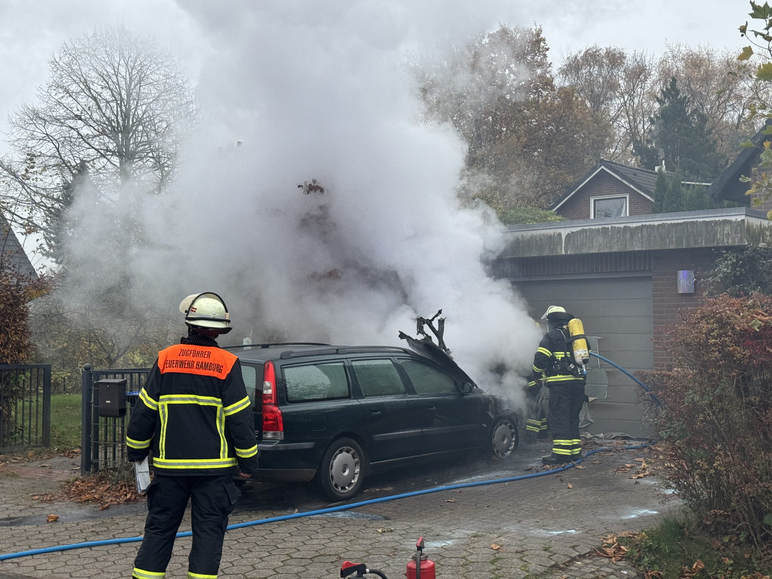 AUs einem Auto steigt Rauch auf. Die Feuerwehr löscht