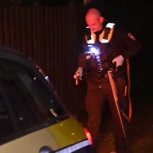 Ein Polizist stellt in Hamburg-Wilhelmsburg das Gewehr sicher, mit dem ein Mann am Halloween-Abend kleine Kinder bedroht hat.