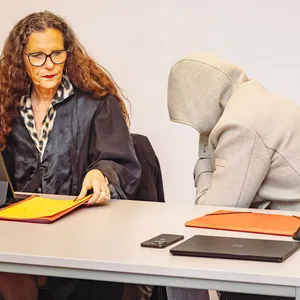 Der des sexuellen Missbrauchs angeklagte Philip W. sitzt zwischen seinen Anwälten, die Kapuze tief ins Gesicht gezogen