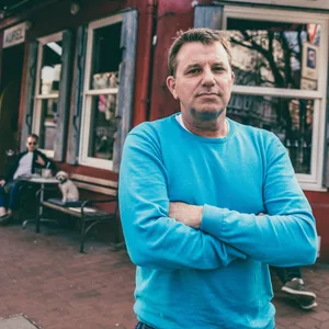 Mann in blauem Pulli vor Kneipe Aurel