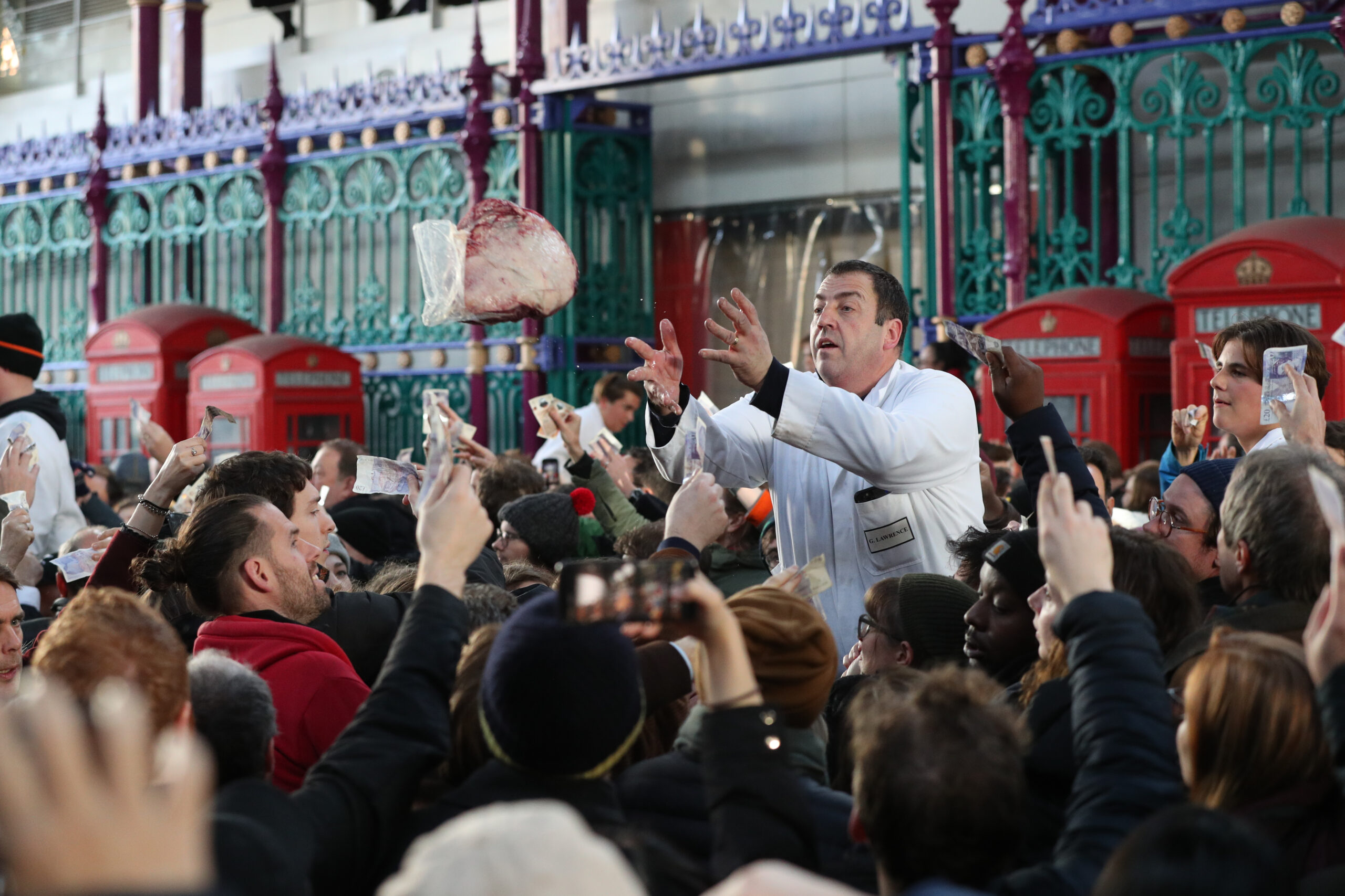 London: Ein Mitarbeiter vom Smithfield Market wirft ein Stück Fleisch zu dem Käufer während der alljährlichen Fleischauktion an Heiligabend.