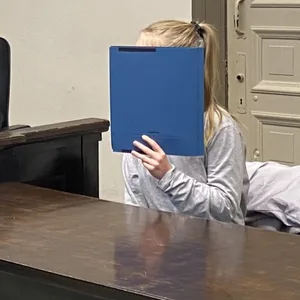 Die Angeklagte Hannah G. hält sich eine blaue Mappe vors Gesicht. Neben ihr sitzt der Verteidiger.