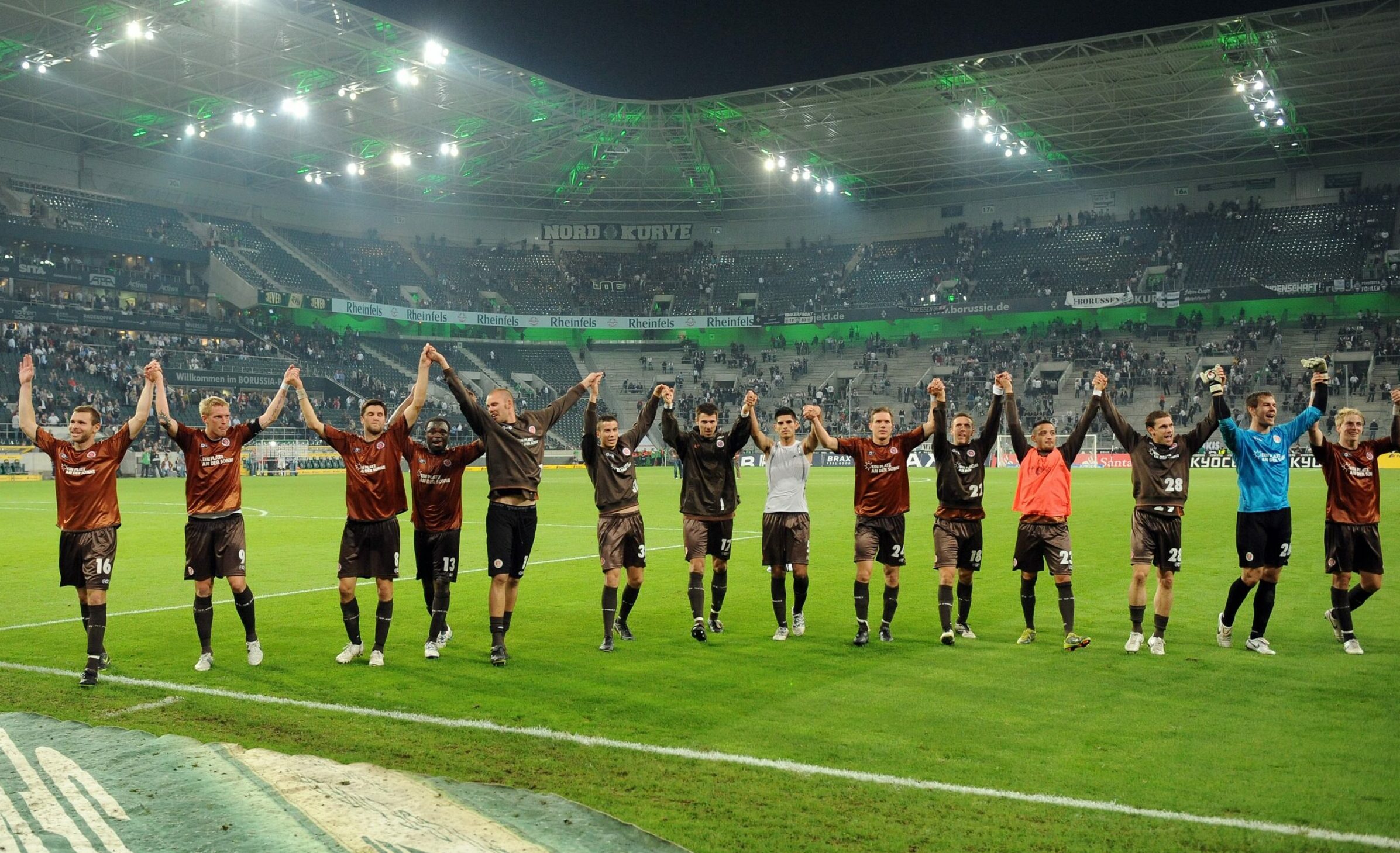 Die St. Pauli-Profis bejubeln Arm in Arm vor der Gästekurve einen Sieg in Mönchenglabach