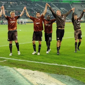 Die St. Pauli-Profis bejubeln Arm in Arm vor der Gästekurve einen Sieg in Mönchenglabach