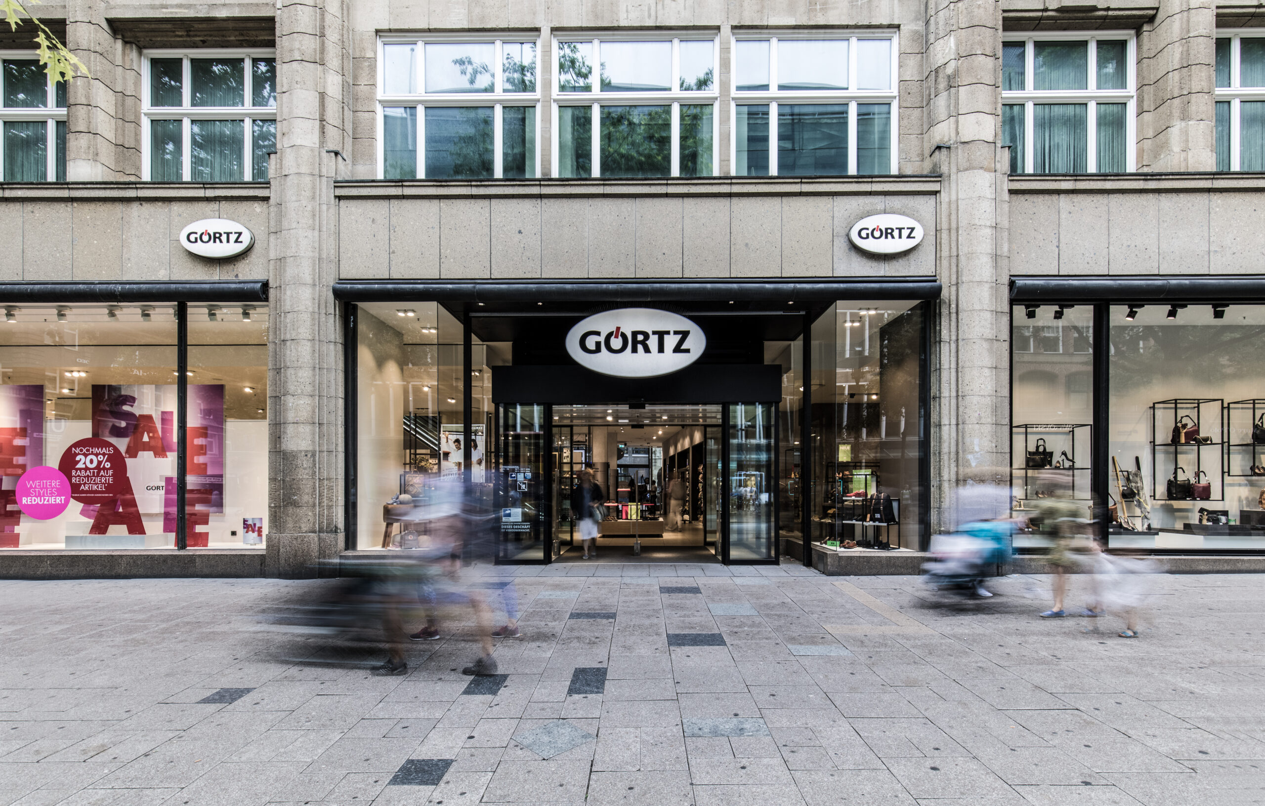 Menschen gehen durch die Innenstadt. Im Hintergrund ist die Görtz Filiale