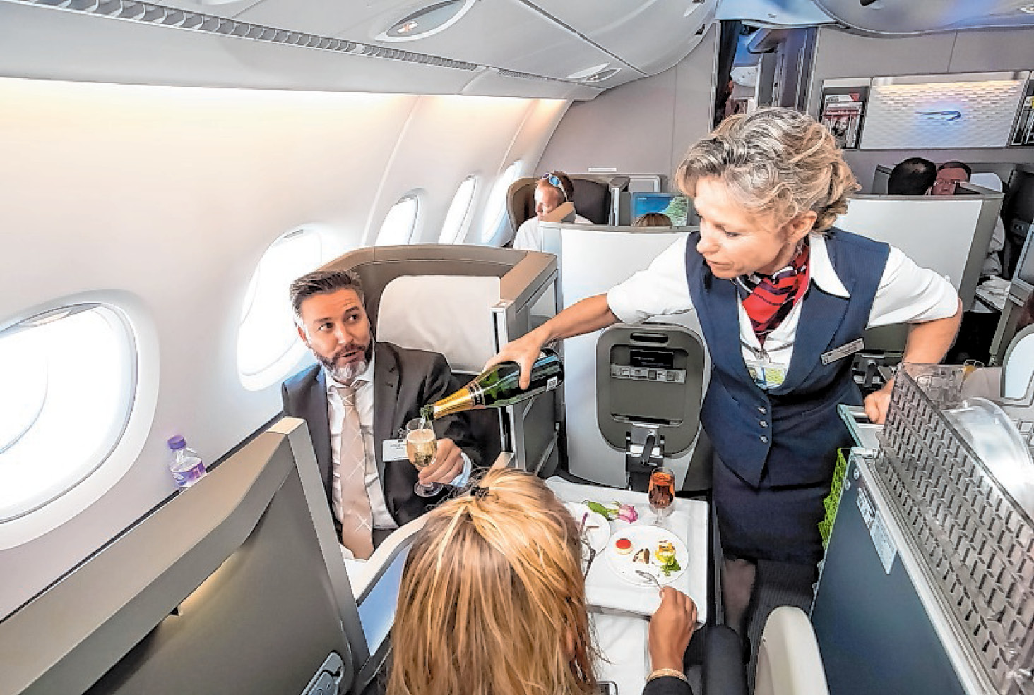 Eine Stewardess schenkt ihren Gästen Champagner ein