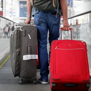 Ein Mann trägt zwei Koffer in einem Flughafen.