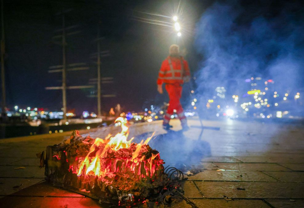 Mitarbeiter der Stadtreinigung Hamburg räumen abgebrannte Feuerwerkskörper und anderen Müll von der Promenade an den Landungsbrücken.