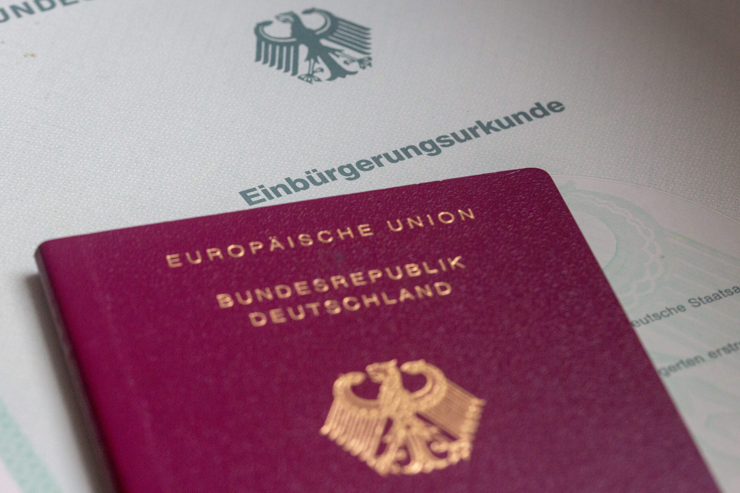 Eine Einbürgerungsurkunde der Bundesrepublik Deutschland und ein deutscher Reisepass liegen auf einem Tisch.