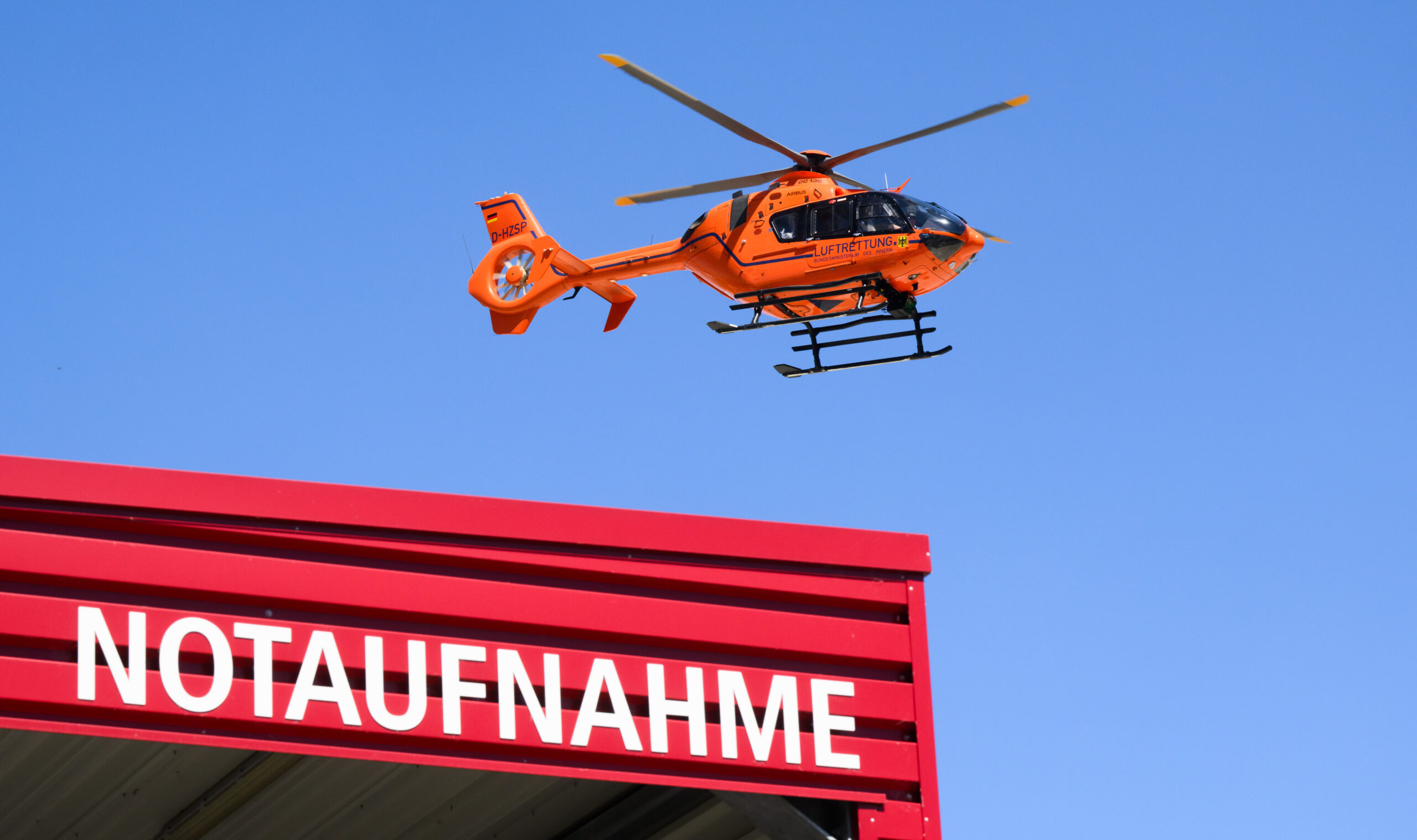 Ein Rettungshubschrauber der Luftrettung fliegt über einer Notaufnahme.