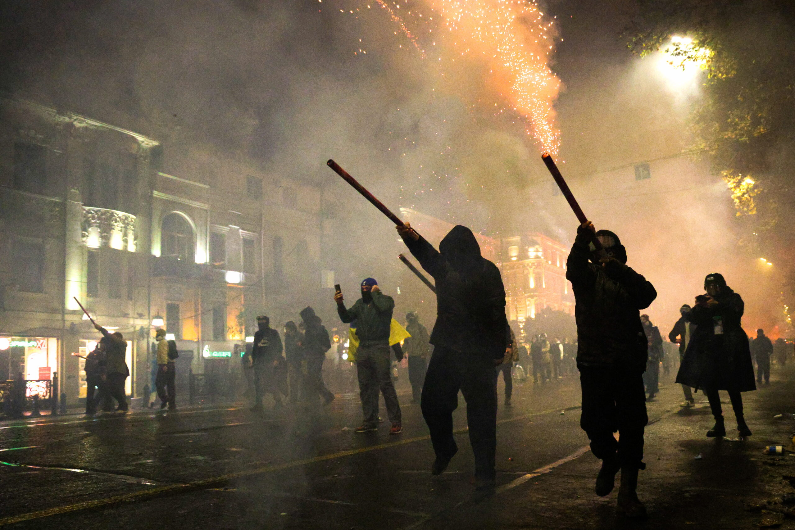 Teilnehmer einer Kundgebung stehen auf der Straße vor dem georgischen Parlament in Tiflis. Demonstranten setzten Feuerwerk gegen die Polizei ein.