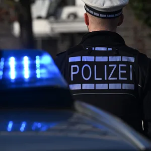 Polizisten stehen an einem Streifenwagen.