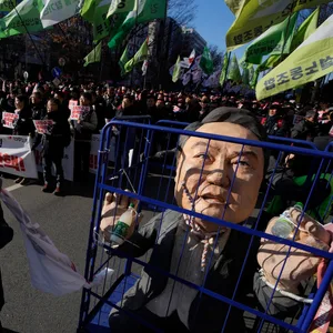 Eine Frau zieht eine Karikatur, die den inhaftierten südkoreanischen Präsidenten zeigt, während Demonstranten in der Nähe der Nationalversammlung seine Amtsenthebung fordern, nachdem das Kriegsrecht verhängt wurde.