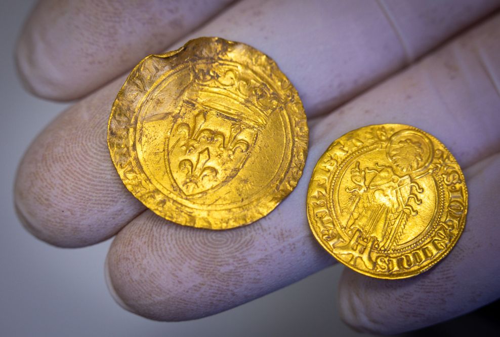 Bei Ausgrabungen in der Nähe von Parchim gefundene Goldmünzen liegen auf einer mit Handschuhe geschützten Hand.