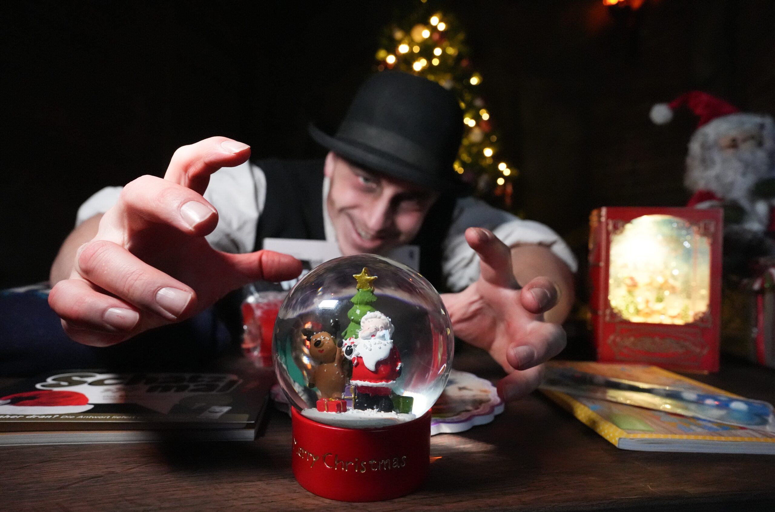 Schauspieler Marcel Casper als Friedrich greift während der Geschenke-Tauschaktion im Hamburg Dungeon nach einer weihnachtlichen Schneekugel.