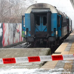 Ein ausgebrannter Zugwaggon steht an einem Bahnsteig.