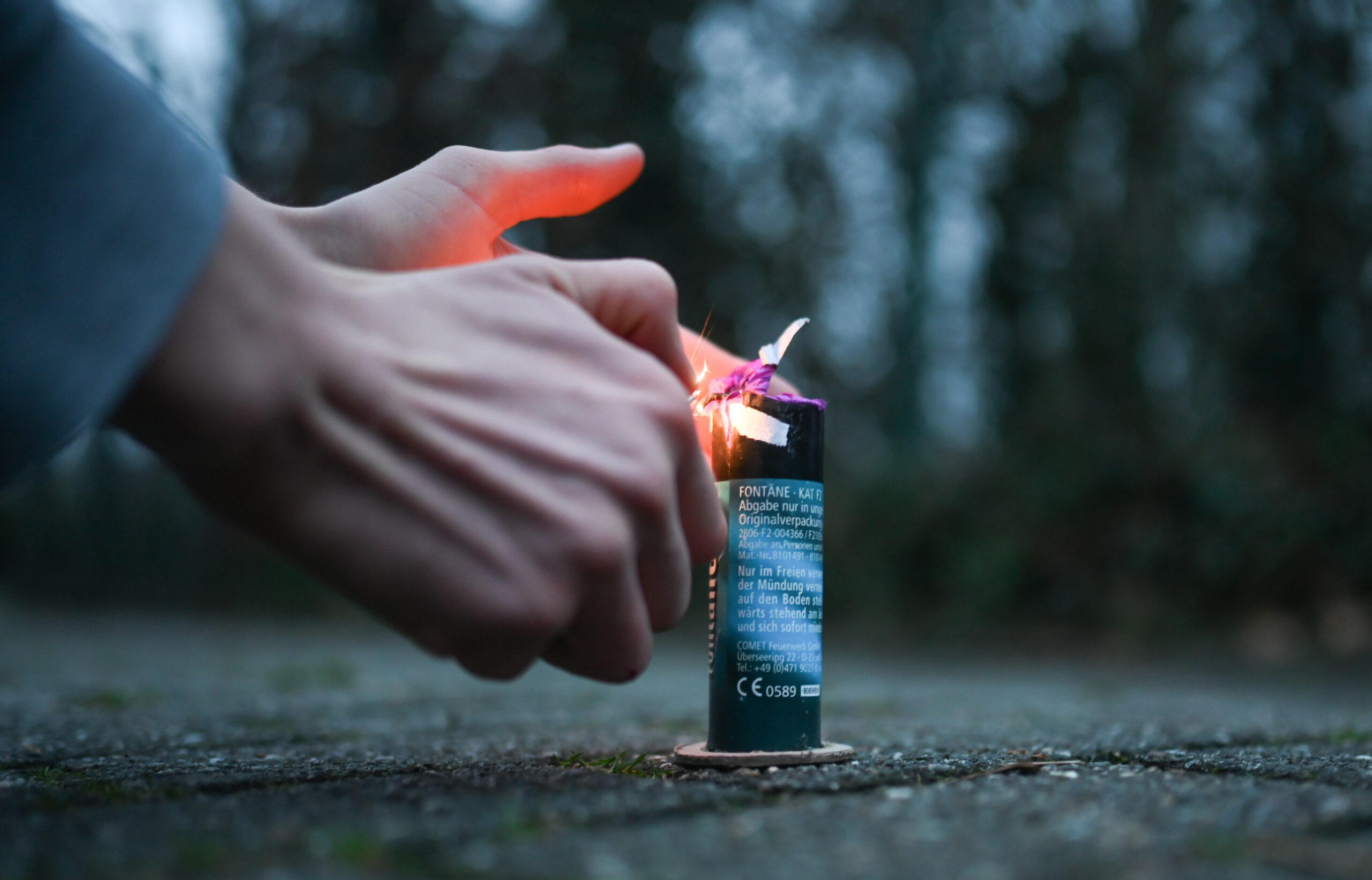 Ein junger Mann zündet eine Feuerwerks-Fontäne an.