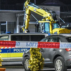 Ein Bagger steht nach einer mutmaßlichen Amokfahrt neben einem Autohaus in Tauberbischofsheim.