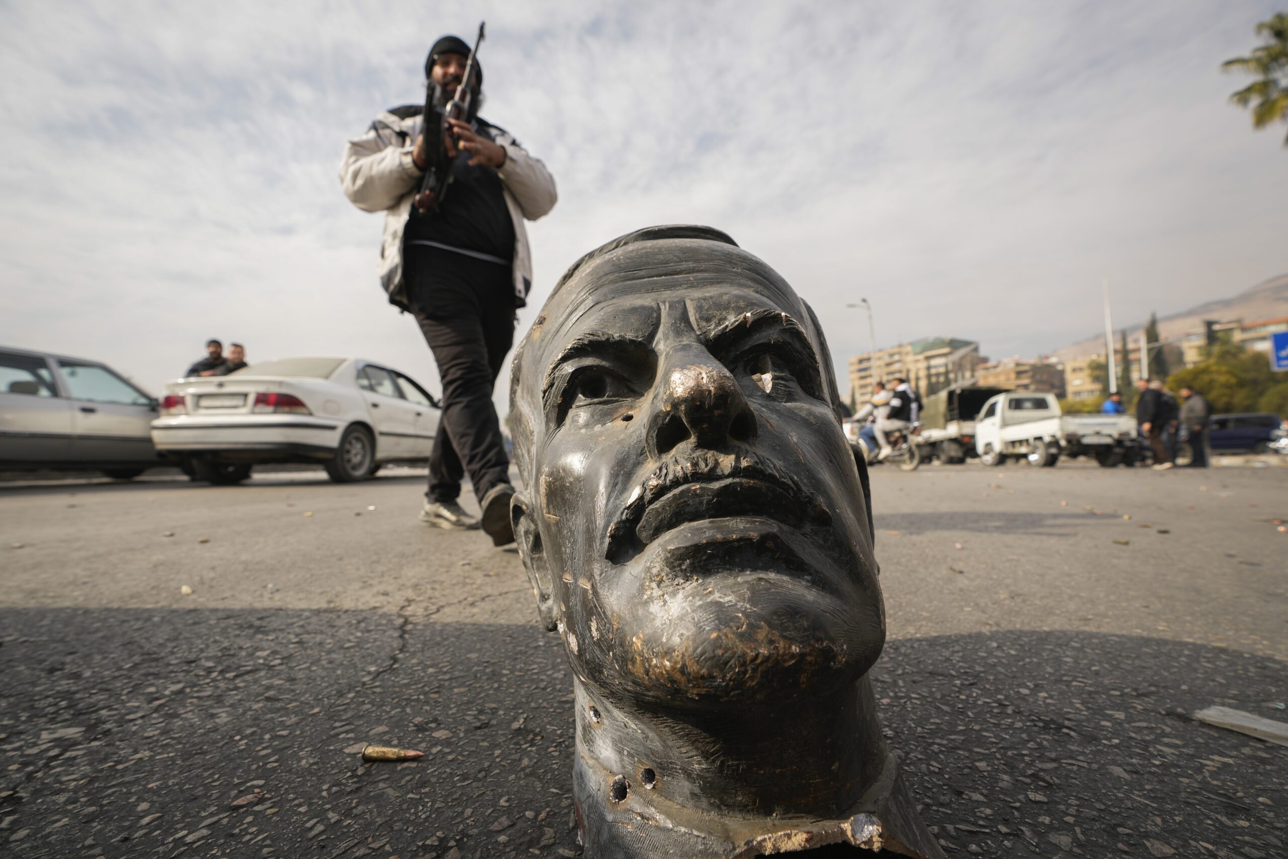 Ein Oppositionskämpfer neben dem abgetrennten Kopf einer Statue des früheren syrischen Präsidenten Hafis al-Assad.