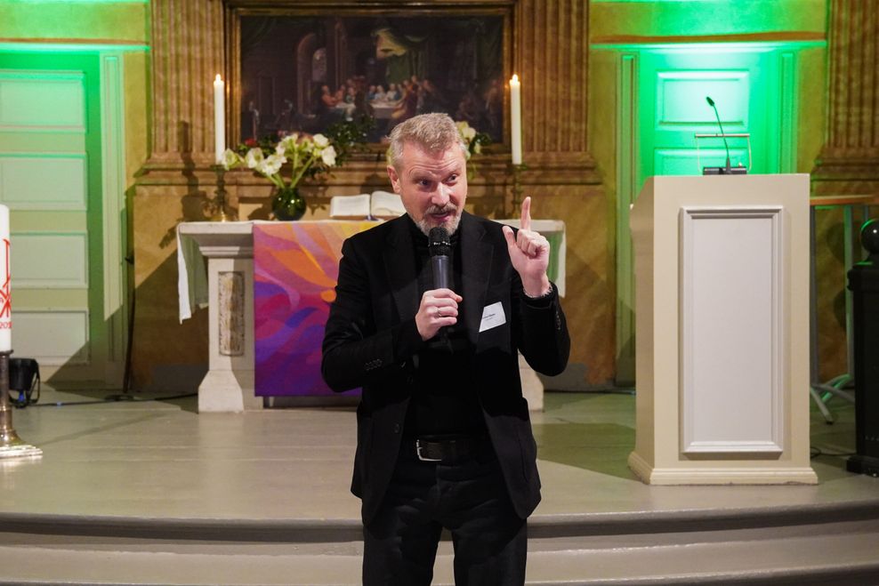 Mann in schwarzem Anzug vor einem Kirchenaltar