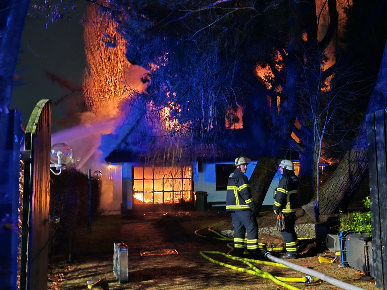 Feuerwehrleute sind vor dem brennenden Haus im Einsatz.