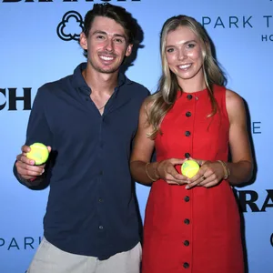 Alex de Minaur und Katie Boulter halten einen Tennisball in der Hand und lächeln in die Kamera.