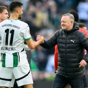 Gladbachs Tim Kleindienst und Geschäftsführer Sport Roland Virkus geben sich einen Handschlag