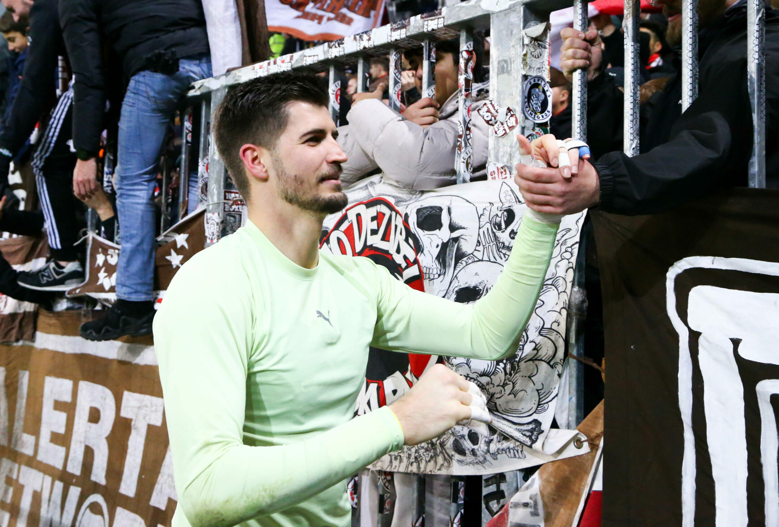 Nikola Vasilj klatscht nach dem Sieg gegen Kiel mit den Fans am Zaun ab.