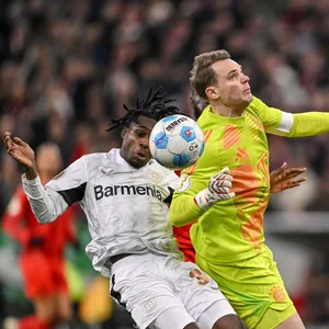 Manuel Neuer steigt rotwürdig gegen Jeremie Frimpong ein.