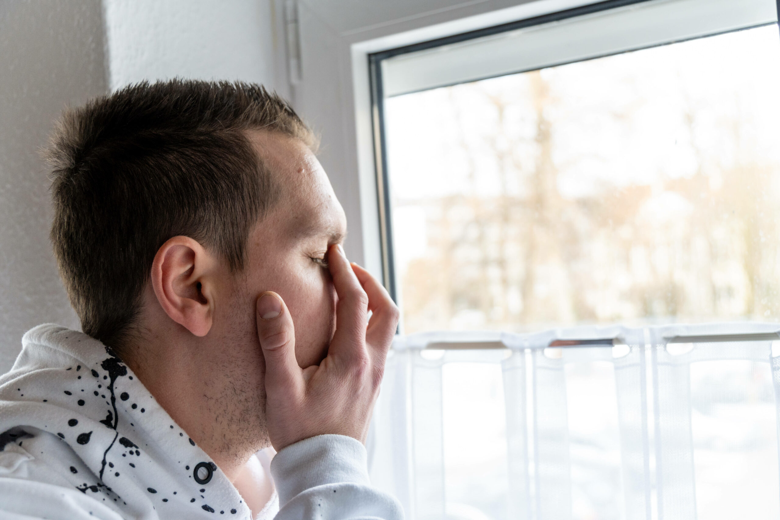 Mann hält sich die Hand vor das Gesicht.