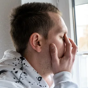 Mann hält sich die Hand vor das Gesicht.