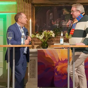 Mann in gestreiftem Pullover interviewt Mann in Anzug
