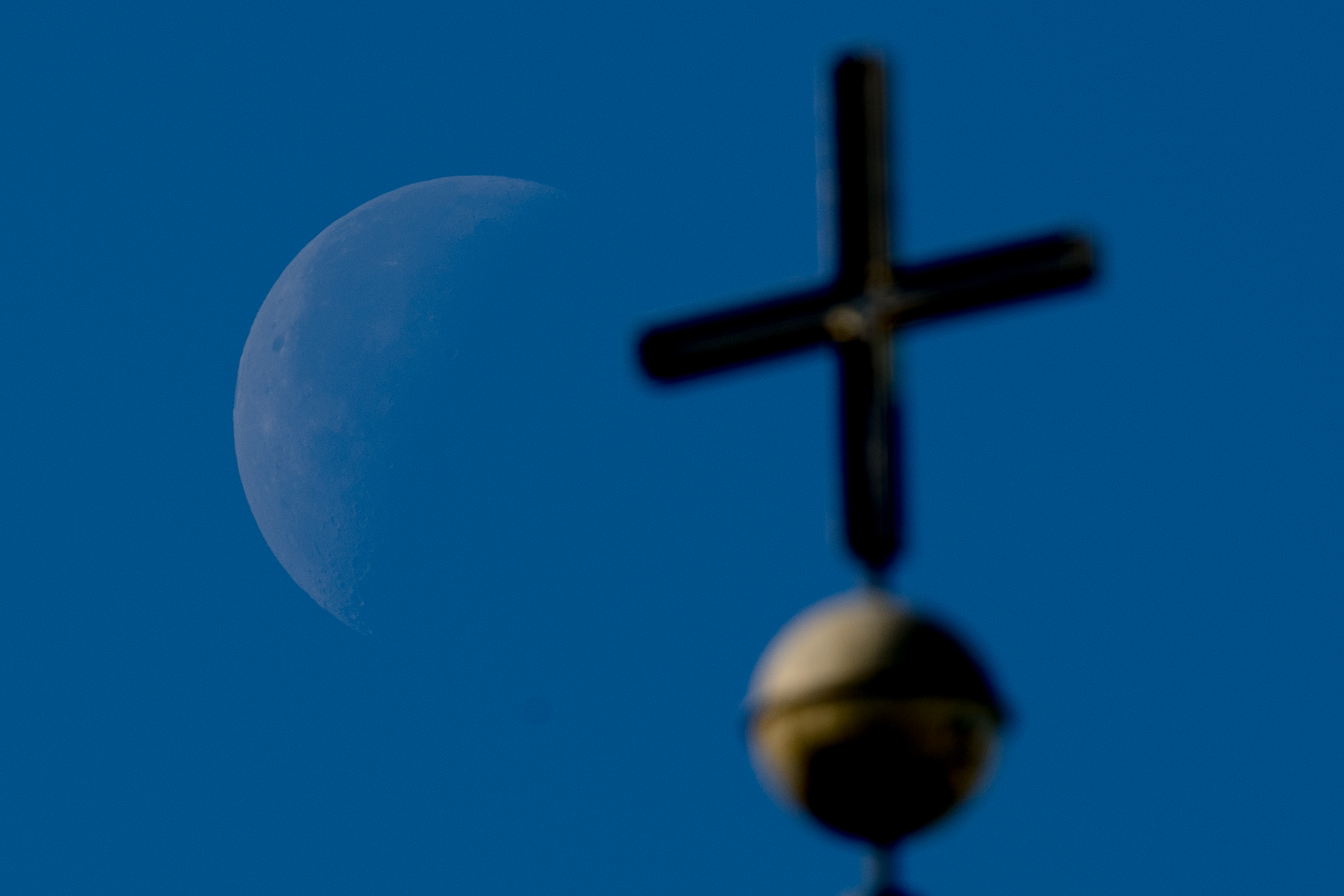 Kreuz auf Kirchturm vor blauem Himmel