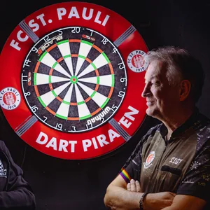Gunnar Wendorf und Sigi Faßbinder stehen vor einer Dartsscheibe und schauen sich an