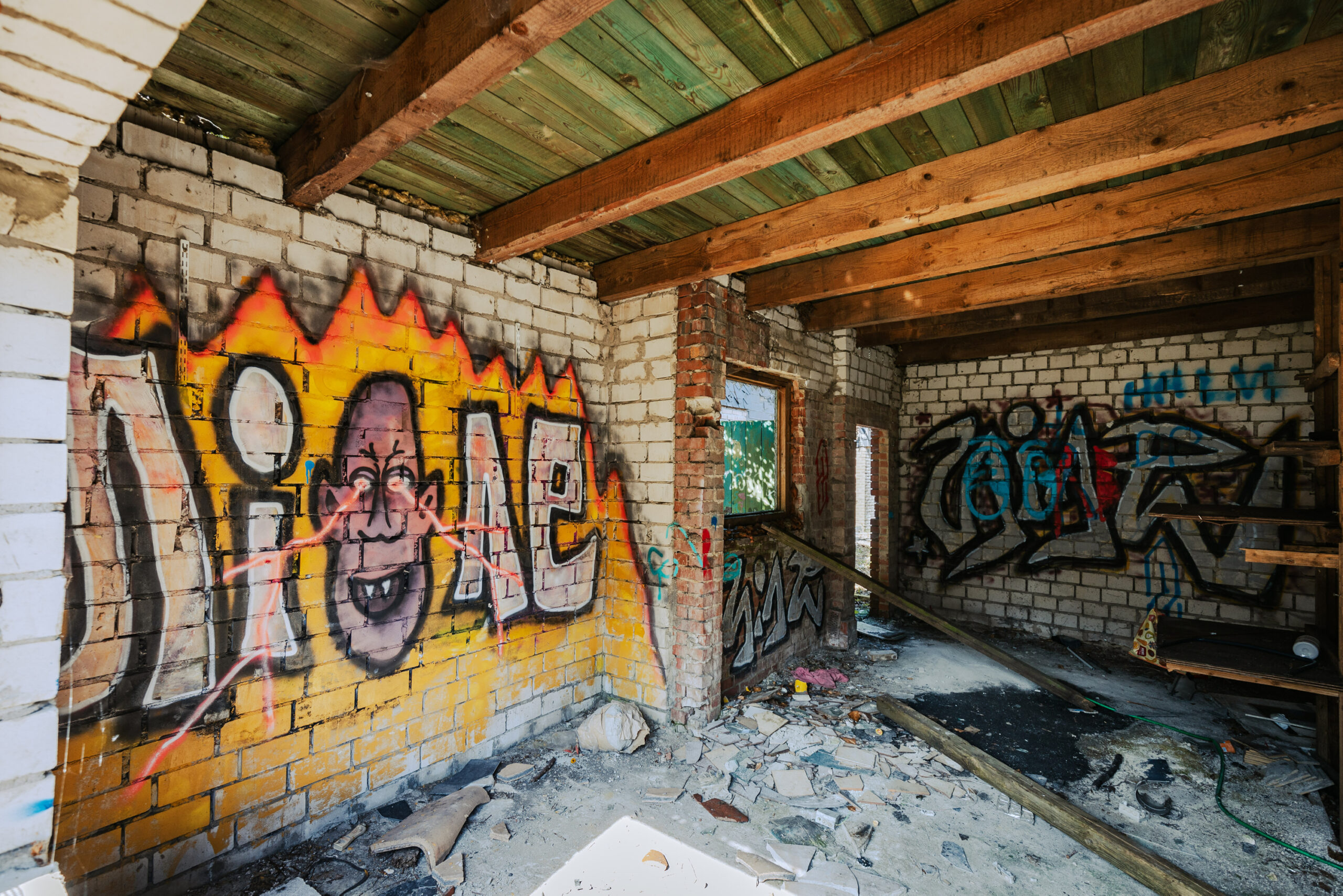 Fantasievolles Graffito im ehemaligen Gerüstbau-Betrieb: Auf einer Flammenwand schießen Blitze aus den Augen einer Fratze.