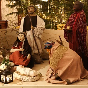 Krippenfiguren stehen vor einem Weihnachtsbaum.