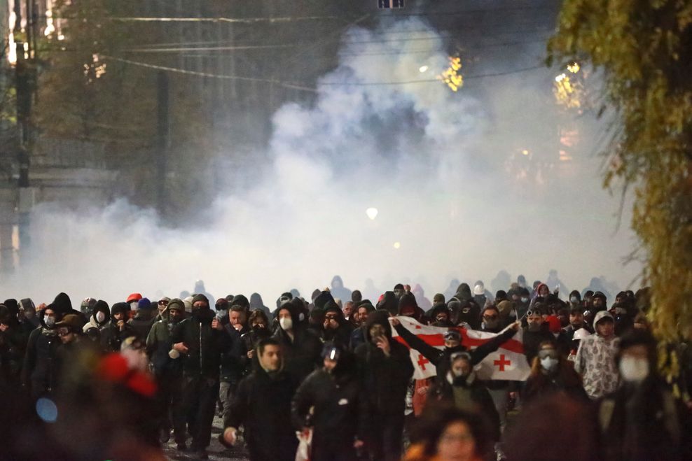 Demonstranten in Tiflis fliehen vor einer Tränengaswolke.